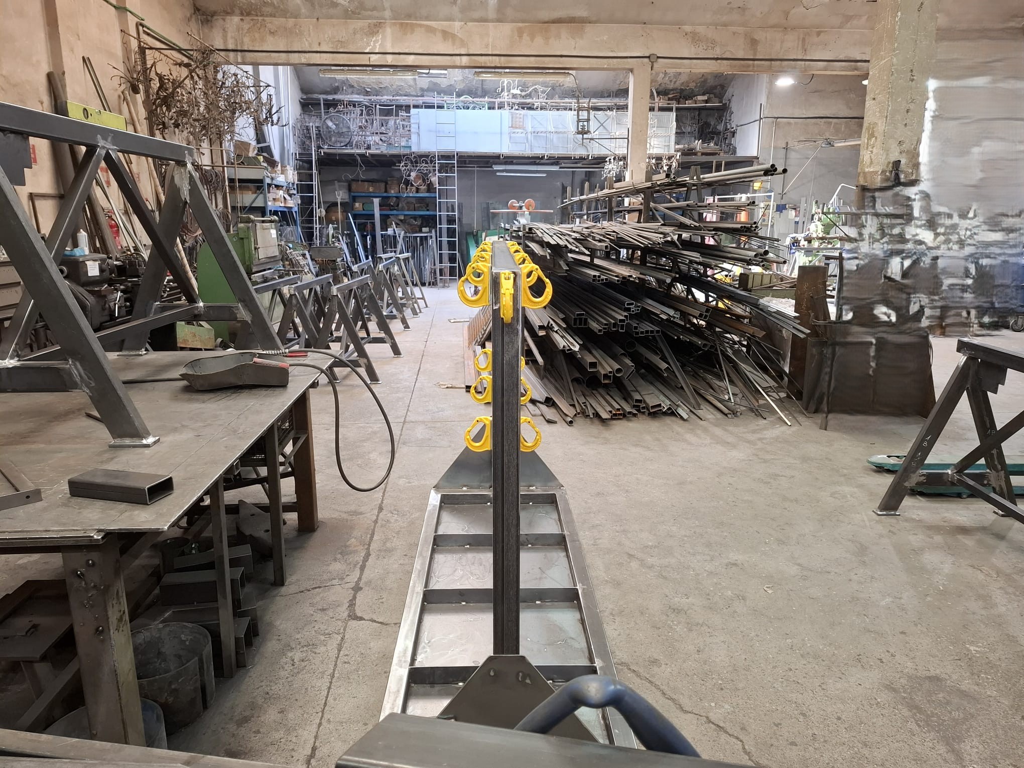 Rastrelliera in acciaio su misura per accessori di sollevamento sottogancio con ganci gialli nell'officina ElisArt