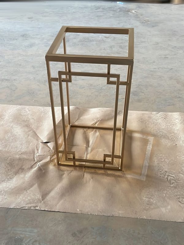 Struttura di scaffale in ferro verniciato oro con decori a greca